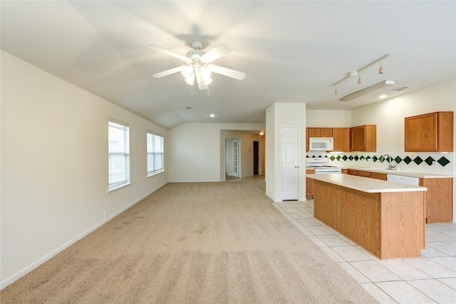 20218 Cypresswood Gln, Spring, TX 77373 - kitchen featuring white appliances, a center island, light countertops, brown cabinetry, and backsplash