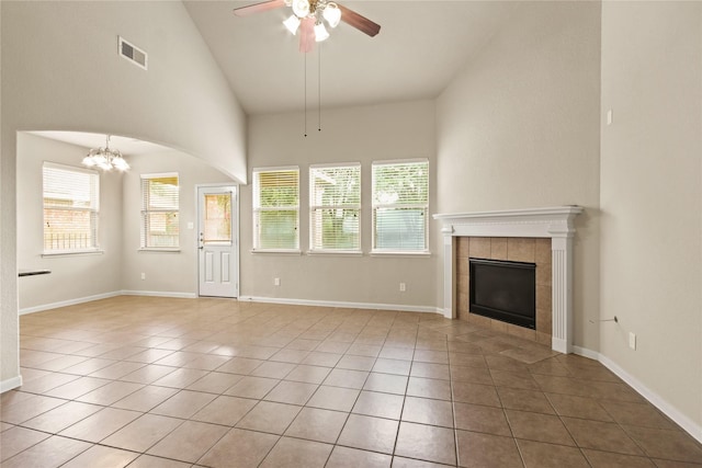 187 Black Swan Pl, The Woodlands, TX 77354 - unfurnished living room with a tiled fireplace, a ceiling fan, a chandelier, light tile patterned flooring, and high vaulted ceiling