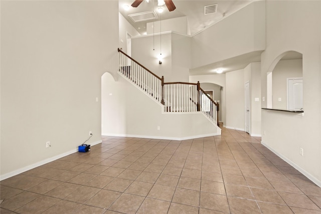 187 Black Swan Pl, The Woodlands, TX 77354 - unfurnished living room featuring arched walkways, a towering ceiling, tile patterned flooring, ceiling fan, and stairs