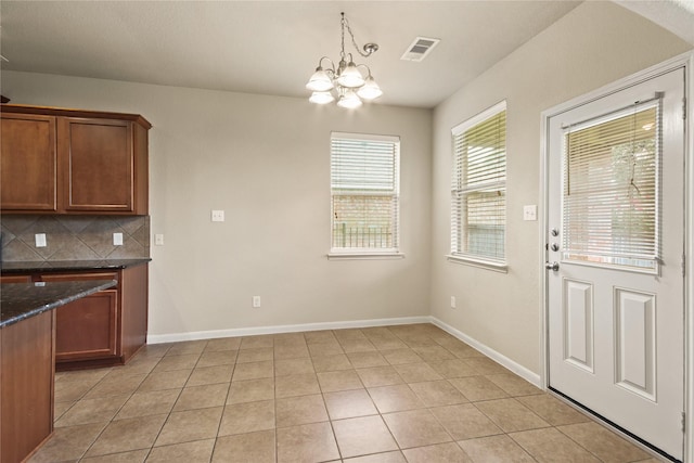 187 Black Swan Pl, The Woodlands, TX 77354 - kitchen with a chandelier, decorative backsplash, light tile patterned floors, pendant lighting, and brown cabinets
