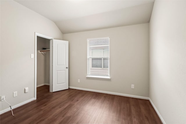 187 Black Swan Pl, The Woodlands, TX 77354 - unfurnished bedroom with dark wood-type flooring, a spacious closet, and vaulted ceiling