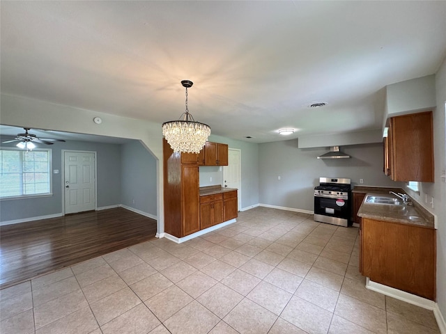 14410 Henry Rd, Houston, TX 77060 - kitchen with stainless steel gas stove, wall chimney exhaust hood, brown cabinetry, light tile patterned floors, and open floor plan