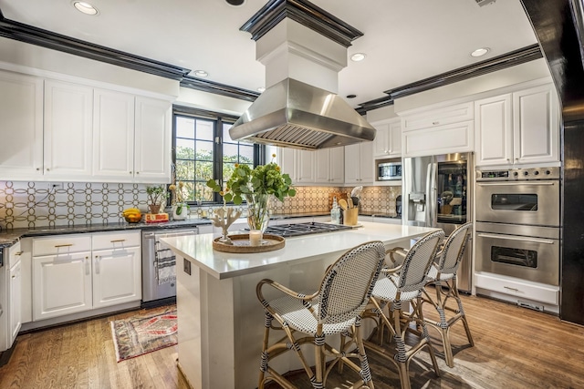2248 Robinhood St, Houston, TX 77005 - kitchen with stainless steel appliances, ornamental molding, white cabinetry, light wood-style floors, and a center island