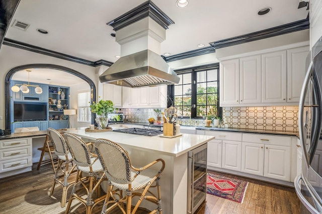 2248 Robinhood St, Houston, TX 77005 - kitchen featuring beverage cooler, crown molding, island range hood, appliances with stainless steel finishes, and dark wood-style floors