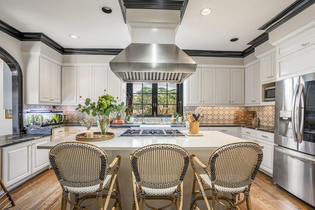 2248 Robinhood St, Houston, TX 77005 - kitchen featuring appliances with stainless steel finishes, island exhaust hood, a kitchen island, white cabinetry, and crown molding