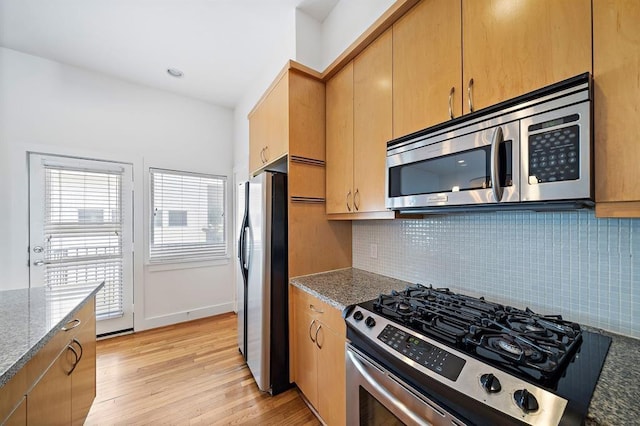 4707 Caroline St, Houston, TX 77004 - kitchen with appliances with stainless steel finishes, tasteful backsplash, light wood-style floors, and dark stone countertops