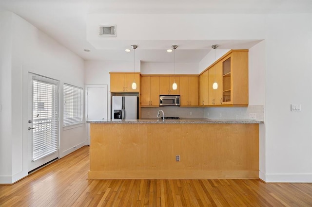 4707 Caroline St, Houston, TX 77004 - kitchen with stainless steel microwave, refrigerator with ice dispenser, a peninsula, light wood finished floors, and recessed lighting