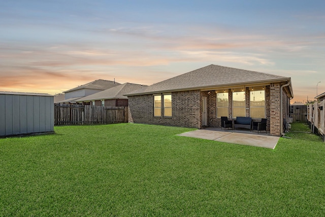 23719 Scotsman Dr, Katy, TX 77493 - back of house at dusk with a patio area, a fenced backyard, a storage unit, brick siding, and a shingled roof