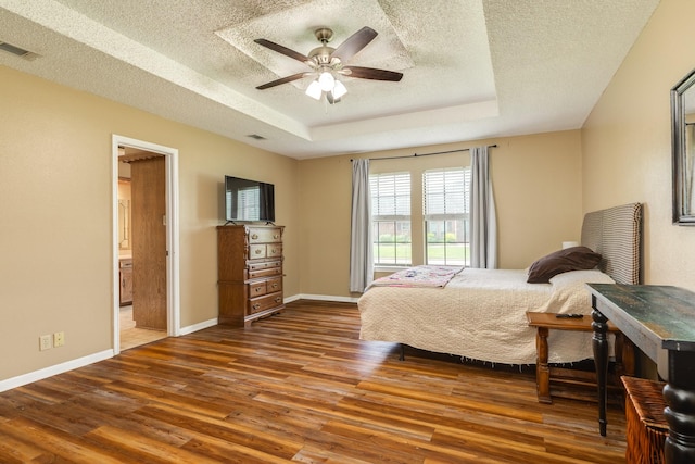108 Laurel Valley Dr, West Columbia, TX 77486 - bedroom featuring wood finished floors, a textured ceiling, a tray ceiling, connected bathroom, and a ceiling fan