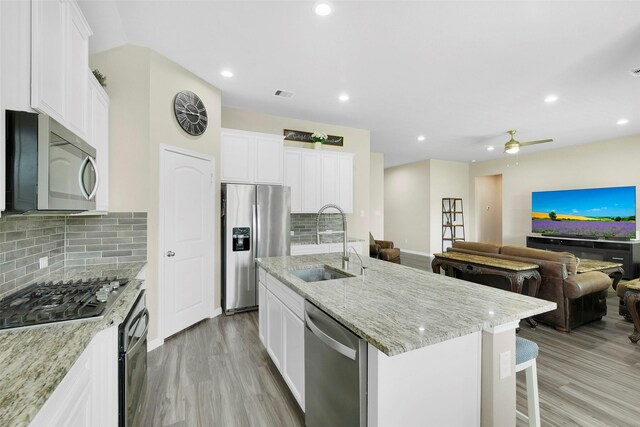 12806 Durham Creek Ln, Tomball, TX 77375 - kitchen with stainless steel appliances, light wood-style flooring, light stone counters, white cabinets, and recessed lighting