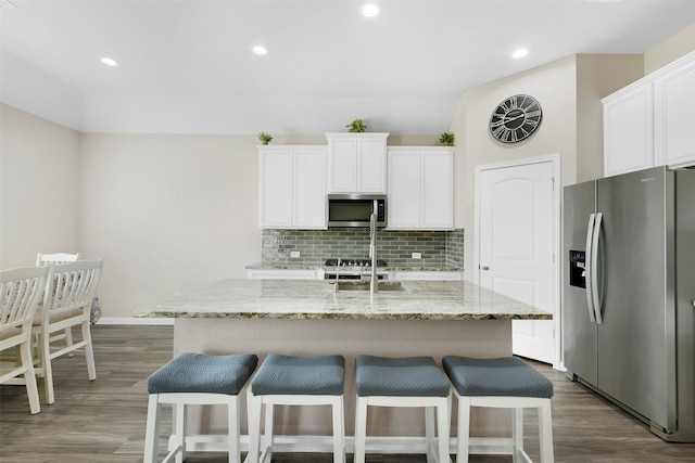 12806 Durham Creek Ln, Tomball, TX 77375 - kitchen with stainless steel appliances, decorative backsplash, a breakfast bar, white cabinetry, and recessed lighting