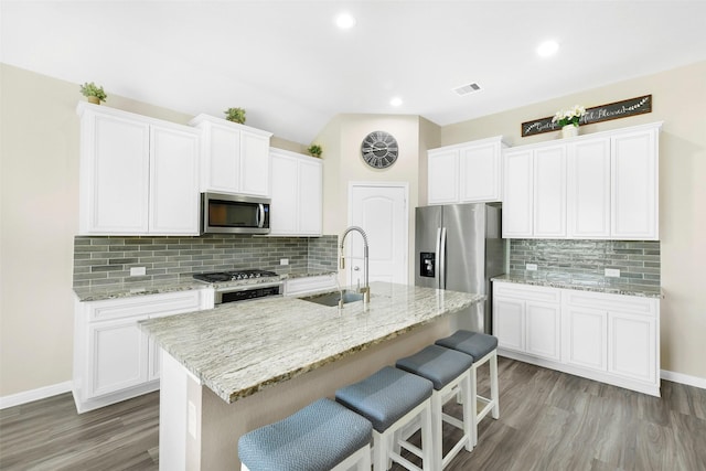 12806 Durham Creek Ln, Tomball, TX 77375 - kitchen with stainless steel appliances, decorative backsplash, a breakfast bar, white cabinetry, and recessed lighting
