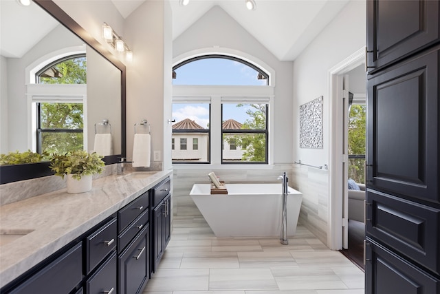 802 Malone St Unit A, Houston, TX 77007 - bathroom featuring tile walls, lofted ceiling, double vanity, a soaking tub, and recessed lighting