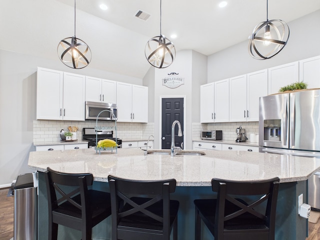 6003 Rivergrove Bend Dr, Humble, TX 77346 - kitchen featuring appliances with stainless steel finishes, dark wood-style flooring, decorative backsplash, vaulted ceiling, and a spacious island