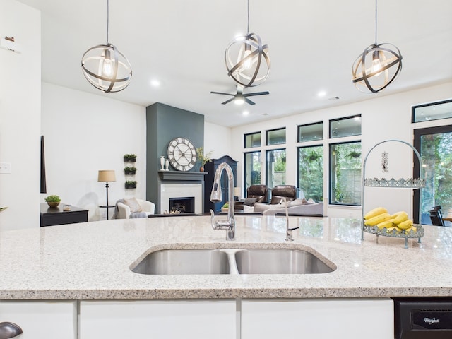 6003 Rivergrove Bend Dr, Humble, TX 77346 - kitchen featuring open floor plan, a fireplace, black dishwasher, pendant lighting, and light stone counters