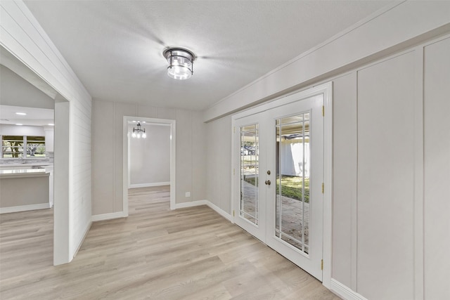 2915 Katy Hockley Rd, Katy, TX 77493 - unfurnished dining area featuring french doors, light wood-style flooring, healthy amount of natural light, a decorative wall, and crown molding