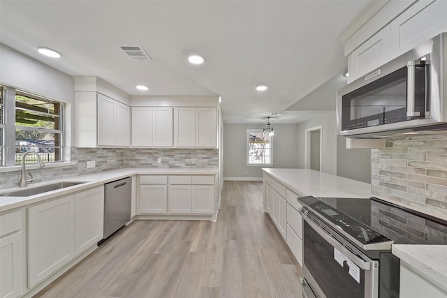 2915 Katy Hockley Rd, Katy, TX 77493 - kitchen featuring appliances with stainless steel finishes, tasteful backsplash, white cabinets, light wood finished floors, and recessed lighting