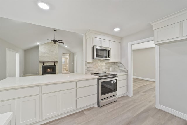 2915 Katy Hockley Rd, Katy, TX 77493 - kitchen featuring stainless steel appliances, a fireplace, ceiling fan, white cabinets, and decorative backsplash
