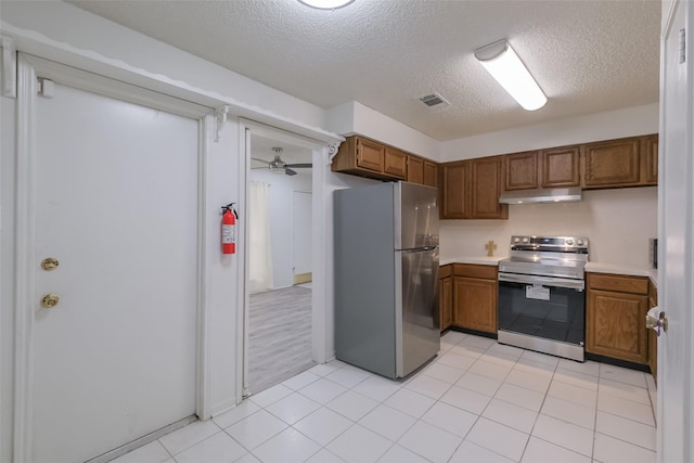 5026 Algernon Dr, Spring, TX 77373 - kitchen featuring appliances with stainless steel finishes, a textured ceiling, brown cabinets, under cabinet range hood, and light countertops