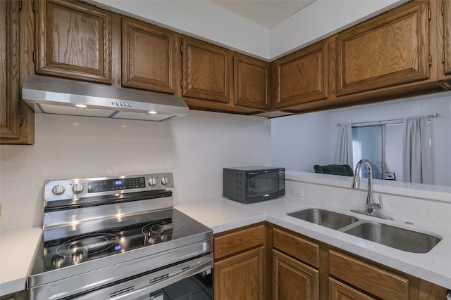 5026 Algernon Dr, Spring, TX 77373 - kitchen with under cabinet range hood, electric stove, black microwave, light countertops, and brown cabinetry