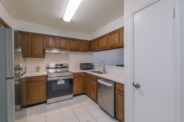 5026 Algernon Dr, Spring, TX 77373 - kitchen featuring stainless steel appliances, under cabinet range hood, brown cabinets, light countertops, and a textured ceiling