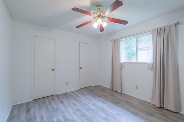 5026 Algernon Dr, Spring, TX 77373 - unfurnished bedroom with light wood-style floors, multiple closets, ceiling fan, and a textured ceiling
