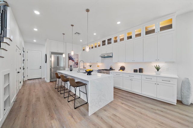 406 E 33rd St, Houston, TX 77018 - kitchen featuring stainless steel appliances, under cabinet range hood, light wood finished floors, a breakfast bar area, and backsplash
