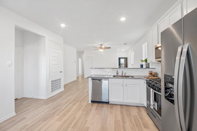 5630 Tabula Rasa Dr, Katy, TX 77493 - kitchen with appliances with stainless steel finishes, a peninsula, a ceiling fan, backsplash, and white cabinets