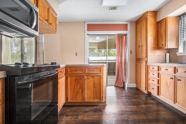 6302 Amie Ln, Pearland, TX 77584 - kitchen with electric range, stainless steel microwave, dark wood-style flooring, brown cabinets, and a textured ceiling