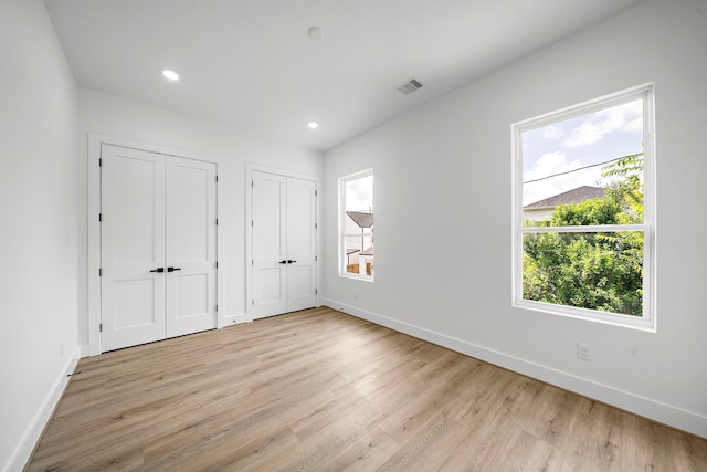 408 E 33rd St, Houston, TX 77018 - unfurnished bedroom with two closets, light wood-type flooring, multiple windows, and recessed lighting
