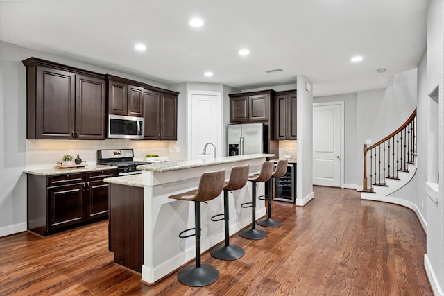 4106 Kolb St, Houston, TX 77007 - kitchen with appliances with stainless steel finishes, beverage cooler, dark brown cabinets, tasteful backsplash, and a kitchen bar