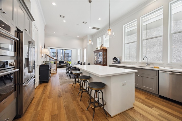 1240 W 16th St, Houston, TX 77008 - kitchen featuring stainless steel appliances, gray cabinets, light wood-style flooring, light countertops, and crown molding