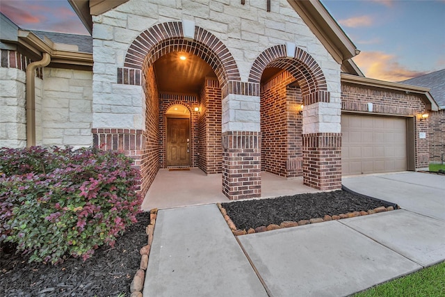 15715 Holloway Creek Ct, Houston, TX 77044 - doorway to property featuring stone siding, concrete driveway, an attached garage, and brick siding
