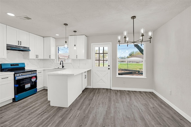 11807 Oceanview St, Missouri City, TX 77071 - kitchen with stainless steel electric range, under cabinet range hood, a peninsula, wood finished floors, and a textured ceiling