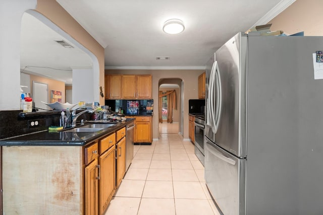 6619 Amberfield Ln, Katy, TX 77449 - kitchen with appliances with stainless steel finishes, arched walkways, light tile patterned floors, brown cabinets, and dark countertops