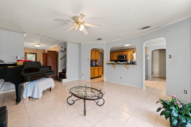 6619 Amberfield Ln, Katy, TX 77449 - living room with arched walkways, a ceiling fan, ornamental molding, light tile patterned floors, and stairway