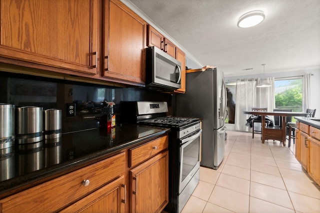 6619 Amberfield Ln, Katy, TX 77449 - kitchen featuring stainless steel appliances, brown cabinets, dark countertops, light tile patterned floors, and pendant lighting