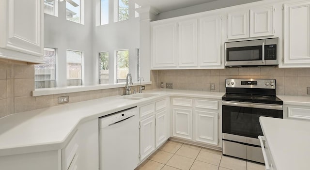 21331 Willow Glade Dr, Katy, TX 77450 - kitchen featuring appliances with stainless steel finishes, light tile patterned flooring, light countertops, white cabinetry, and tasteful backsplash
