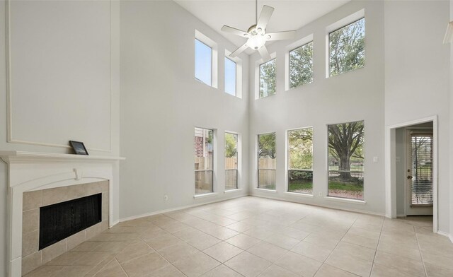 21331 Willow Glade Dr, Katy, TX 77450 - unfurnished living room featuring ceiling fan, plenty of natural light, a high ceiling, a tile fireplace, and light tile patterned floors