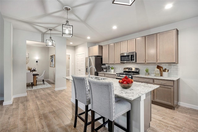 308 Spruce Oak Ln, Waller, TX 77484 - kitchen with stainless steel appliances, light wood-style floors, a breakfast bar, tasteful backsplash, and a center island with sink