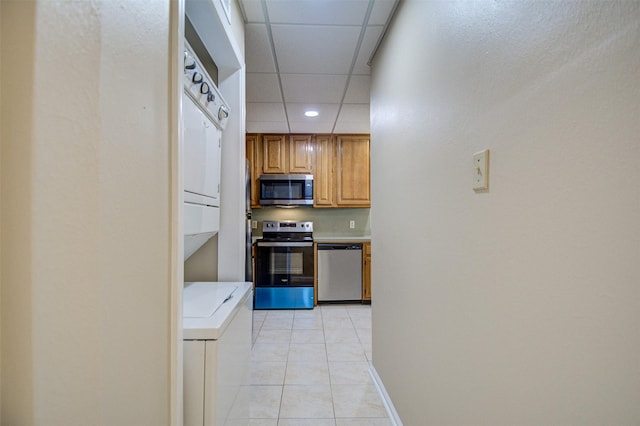 2213 S Braeswood Blvd Unit 13C, Houston, TX 77030 - kitchen featuring appliances with stainless steel finishes, stacked washer / dryer, light tile patterned flooring, recessed lighting, and a paneled ceiling