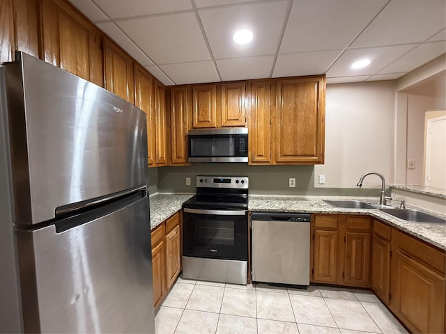 2213 S Braeswood Blvd Unit 13C, Houston, TX 77030 - kitchen featuring stainless steel appliances, brown cabinets, light tile patterned floors, a paneled ceiling, and light stone counters