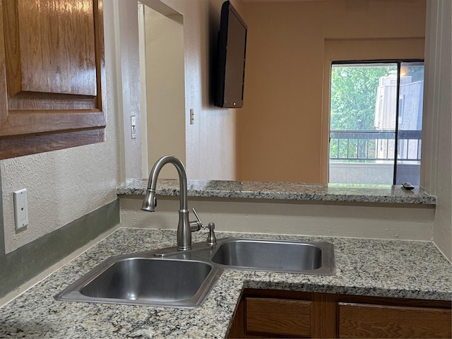 2213 S Braeswood Blvd Unit 13C, Houston, TX 77030 - kitchen with a textured wall, brown cabinetry, and light stone counters