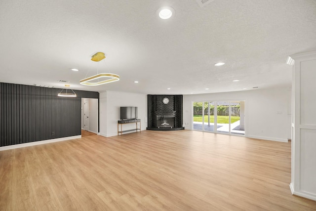 4302 Wigton Dr, Houston, TX 77096 - unfurnished living room featuring light wood finished floors, recessed lighting, a brick fireplace, and a textured ceiling