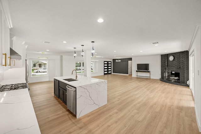4302 Wigton Dr, Houston, TX 77096 - kitchen featuring appliances with stainless steel finishes, light wood-style floors, a fireplace, recessed lighting, and pendant lighting
