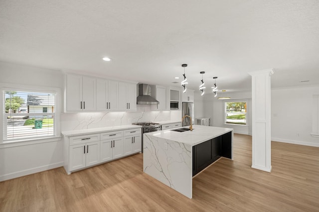 4302 Wigton Dr, Houston, TX 77096 - kitchen with wall chimney exhaust hood, appliances with stainless steel finishes, light wood-style flooring, a center island with sink, and recessed lighting