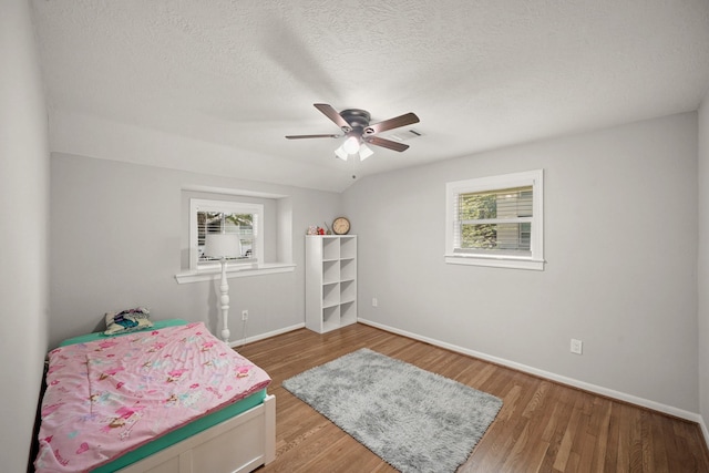 4302 Wigton Dr, Houston, TX 77096 - bedroom with multiple windows, wood finished floors, a textured ceiling, and ceiling fan