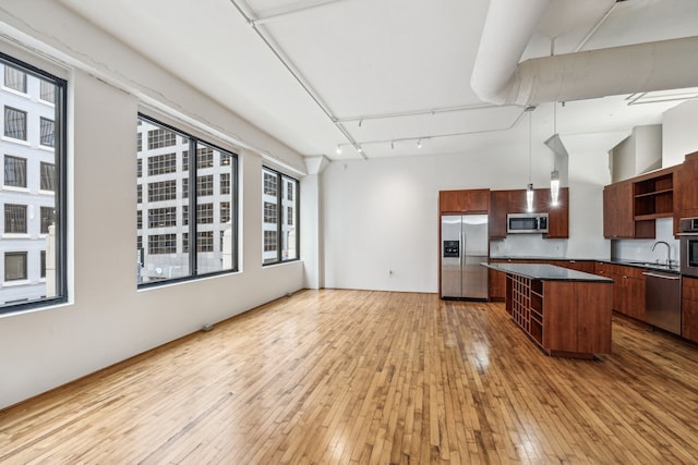705 Main St Unit 302, Houston, TX 77002 - kitchen featuring appliances with stainless steel finishes, open shelves, dark countertops, light wood-type flooring, and a center island