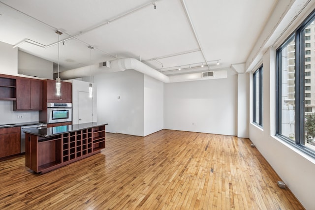 705 Main St Unit 302, Houston, TX 77002 - kitchen featuring stainless steel appliances, open shelves, dark countertops, light wood-type flooring, and a center island