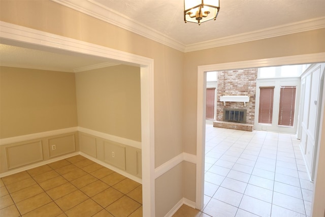 20246 Pittsford Dr, Katy, TX 77450 - hall featuring ornamental molding, light tile patterned floors, a decorative wall, a wainscoted wall, and a chandelier